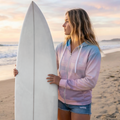 Woman holding a surfboard on a beach at sunset